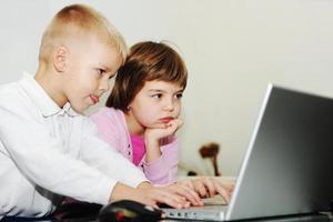 los niños se divierten y juegan en la computadora portátil foto