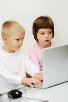 childrens have fun and playing games on laptop computer photo