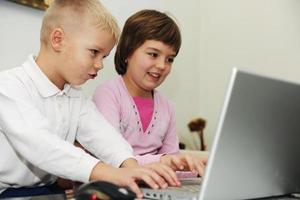 los niños se divierten y juegan en la computadora portátil foto