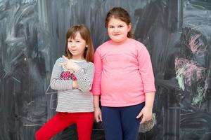 portrait of little girls in front of chalkboard photo