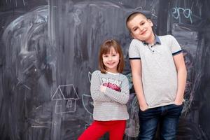 niño y niña parados frente a la pizarra foto