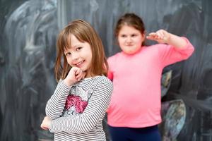 portrait of little girls in front of chalkboard photo