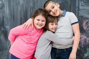 grupo de niños abrazándose frente a la pizarra foto