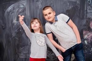 niño y niña parados frente a la pizarra foto