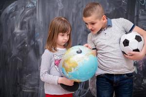 niño y niña usando el globo terráqueo frente a la pizarra foto