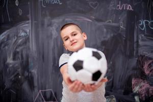 happy boy holding a soccer ball in front of chalkboard photo