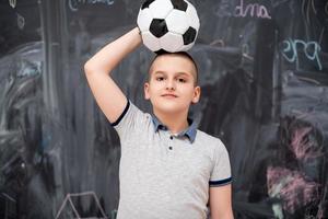 niño feliz sosteniendo un balón de fútbol en la cabeza foto