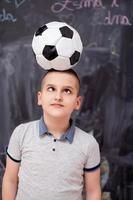 niño feliz sosteniendo un balón de fútbol en la cabeza foto