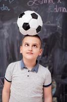 happy boy holding a soccer ball on his head photo