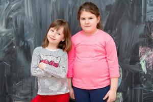 portrait of little girls in front of chalkboard photo