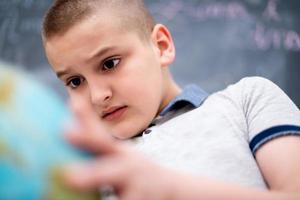 boy using globe of earth in front of chalkboard photo