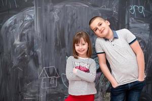 niño y niña parados frente a la pizarra foto