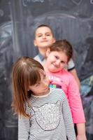 group of kids standing in front of chalkboard photo