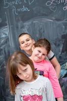 group of kids standing in front of chalkboard photo