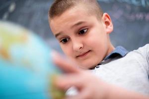 boy using globe of earth in front of chalkboard photo