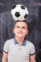 niño feliz sosteniendo un balón de fútbol en la cabeza foto