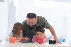 padre soltero en casa con dos niños jugando juegos en tableta foto