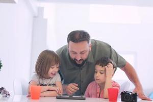 single father at home with two kids playing games on tablet photo