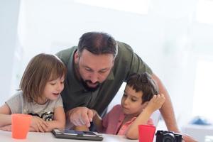 single father at home with two kids playing games on tablet photo