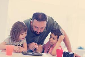 single father at home with two kids playing games on tablet photo