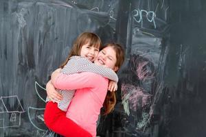 little girls hugging in front of chalkboard photo