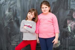 portrait of little girls in front of chalkboard photo