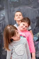 group of kids standing in front of chalkboard photo