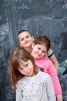 group of kids standing in front of chalkboard photo