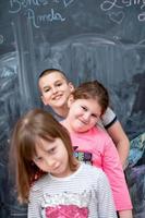 group of kids standing in front of chalkboard photo