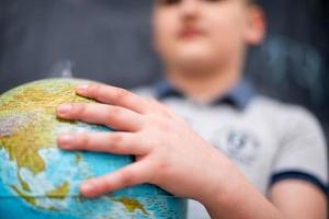 boy using globe of earth in front of chalkboard photo