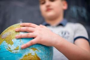 boy using globe of earth in front of chalkboard photo