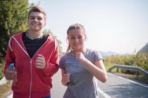 young couple jogging along a country road photo