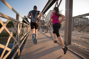 pareja joven corriendo por el puente en la ciudad foto