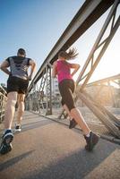 pareja joven corriendo por el puente en la ciudad foto