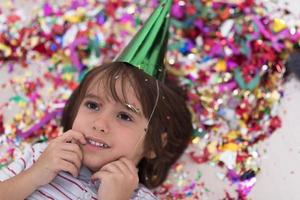 kid blowing confetti while lying on the floor photo