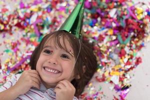 kid blowing confetti while lying on the floor photo
