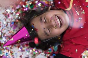 kid blowing confetti while lying on the floor photo