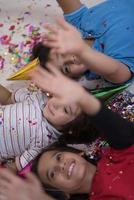 kids  blowing confetti while lying on the floor photo