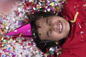 kid blowing confetti while lying on the floor photo