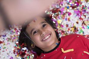 kid blowing confetti while lying on the floor photo