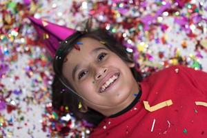 kid blowing confetti while lying on the floor photo