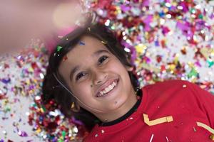 kid blowing confetti while lying on the floor photo