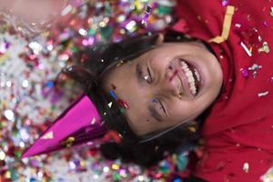 kid blowing confetti while lying on the floor photo