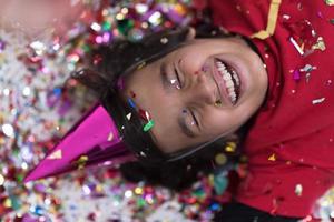 kid blowing confetti while lying on the floor photo