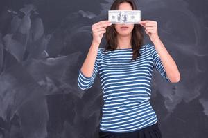 mujer sosteniendo un billete frente a un tablero de dibujo de tiza foto