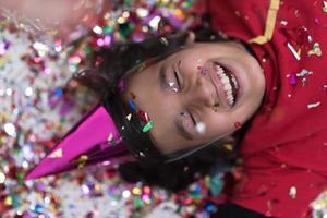 kid blowing confetti while lying on the floor photo