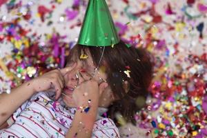 kid blowing confetti while lying on the floor photo