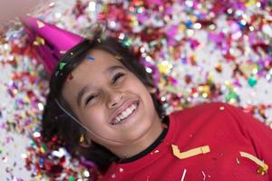 kid blowing confetti while lying on the floor photo