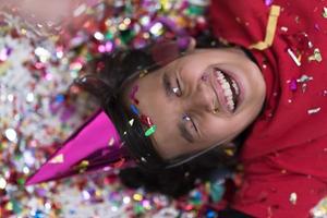 kid blowing confetti while lying on the floor photo