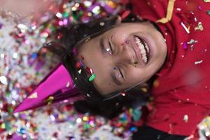 kid blowing confetti while lying on the floor photo